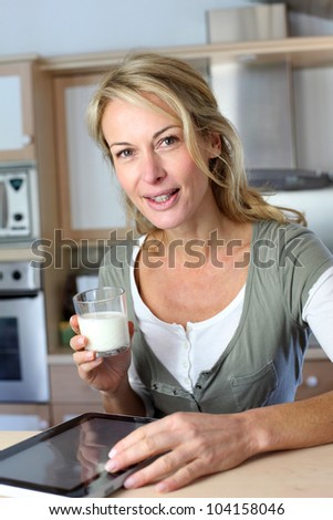 Portrait of blond woman drinking milk in home kitchen