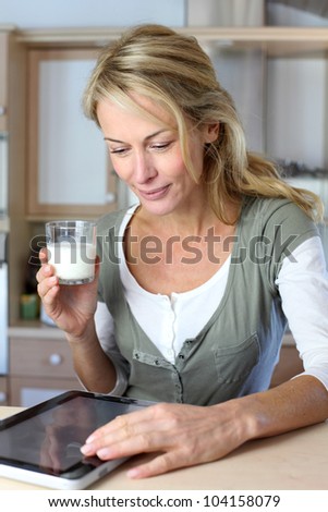 Portrait of blond woman drinking milk in home kitchen
