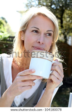 Portrait of blond woman with tea mug sitting outside