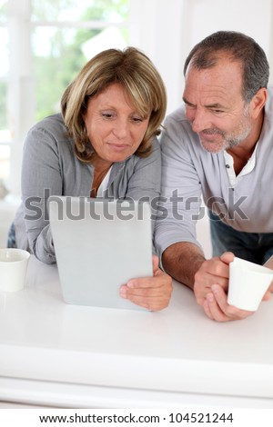 Senior couple drinking coffee in front of tablet