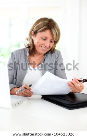 Senior woman using internet to get some help with paper work