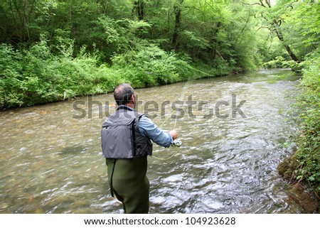 Back view of fisherman in river fly fishing