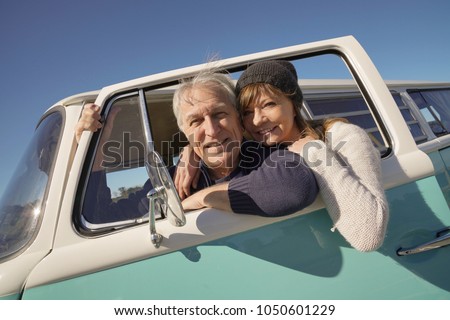 Happy senior couple traveling with vintage van by the ocean