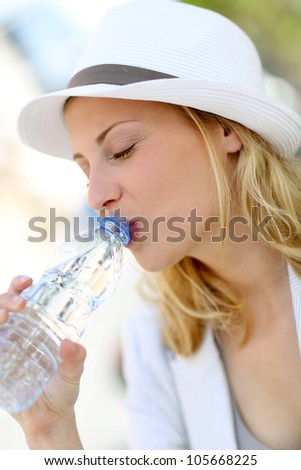 Beautiful blond girl drinking water from bottle