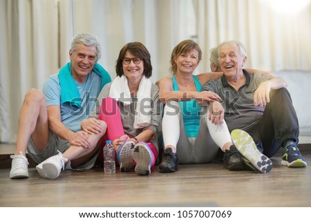 Group of senior people sitting on floor in fitness room