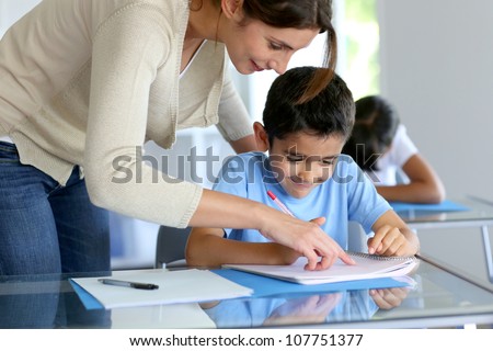 Teacher helping young boy with writing lesson
