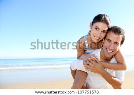 Man carrying girlfriend on his back at the beach