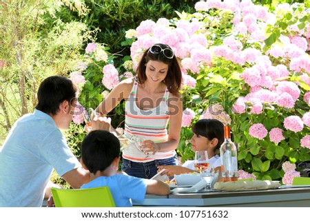 Woman serving water to family having lunch