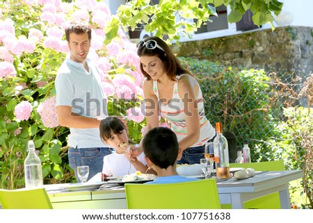 Mother serving lunch to kids in home garden