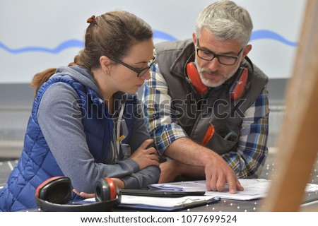 Industrial woodwork technicians reading blueprint