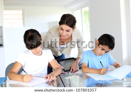 Teacher and kids in classroom writing on notebook