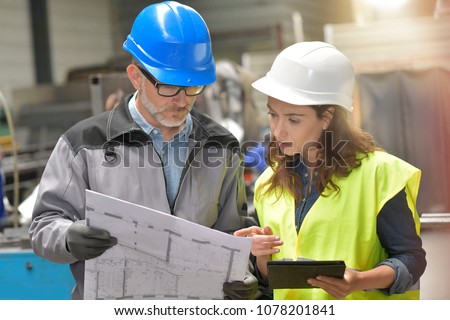 Metalworker and engineer meeting in factory