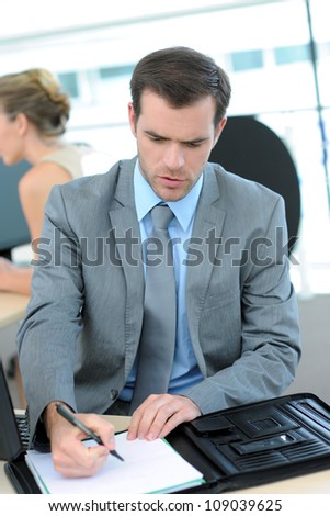 Businessman writing on document in office