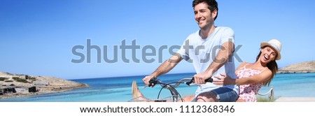 Man giving bike ride to girlfriend on beautiful Island, template