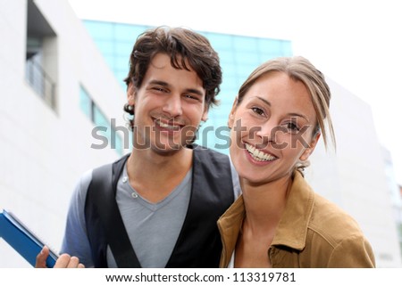 Cheerful couple of students standing on college campus