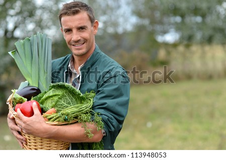 Portrait of smiling farmer holding vegetables basket