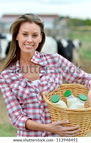 Smiling young farmer carrying bottles of fresh milk