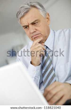 Senior man with puzzled look in front of laptop