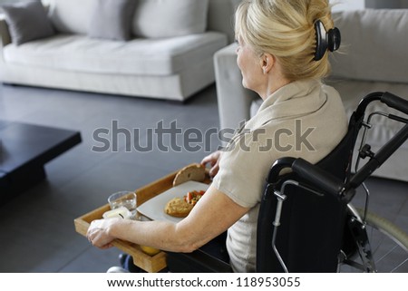 Senior woman in wheelchair holding lunch tray
