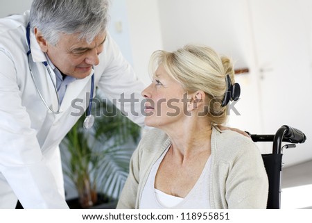 Portrait of surgeon talking to patient in wheelchair