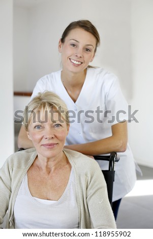 Nurse at home with elderly person in wheelchair