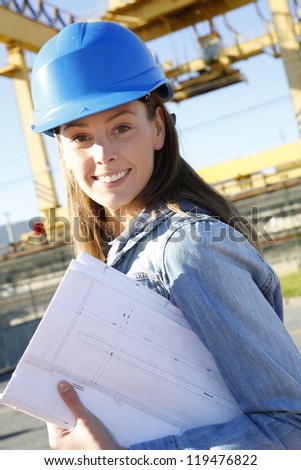 Woman engineer standing on construction site with plan