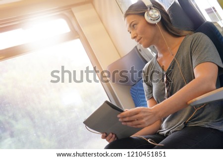 Young woman travelling by train with tablet and headphones