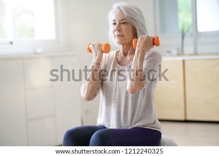 Attractive elderly woman exercising at home with swiss ball