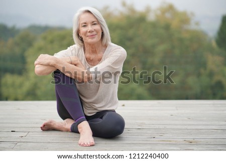 Beautiful elderly woman sitting outdoors in sportswear