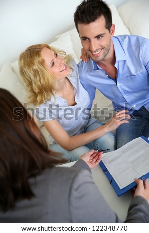 Cheerful couple signing property contract with real-estate agent