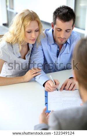 Real Estate Contract on Cheerful Couple Signing Property Contract With Real Estate Agent Stock