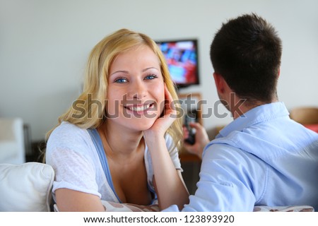 Smiling blond girl watching tv with boyfriend