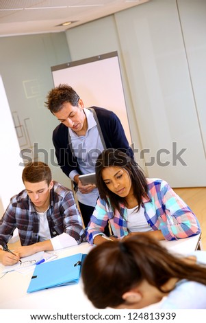 Teacher controlling group of students with paperwork