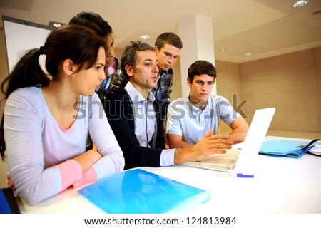 Teacher with students in class working on laptop
