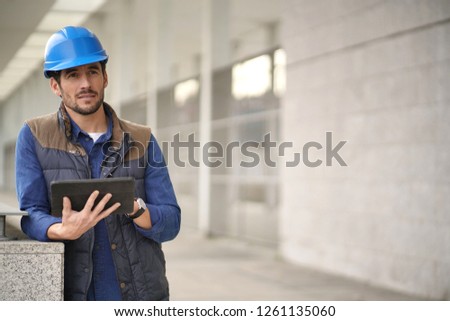 Attractive building expert in hardhat checking sight with tablet
