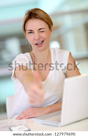 Woman in front of laptop showing thumb up