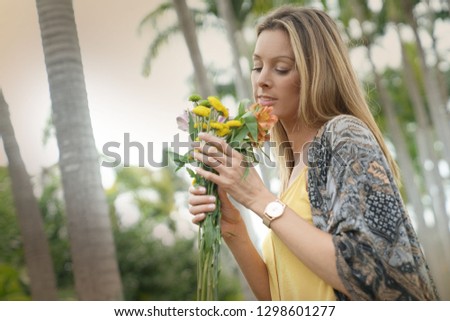 Beautiful bohemain woman holding bouquet of flowers surrounded by palm trees