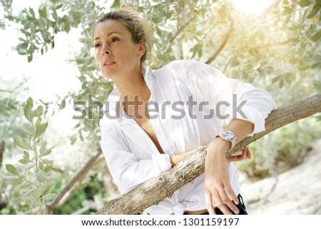 Stunning young woman in open white shirt  surrounded by rustic trees