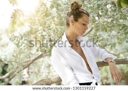 Stunning young woman in open white shirt  surrounded by rustic trees