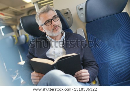Mature man traveling by train, reading book