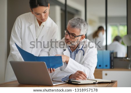 Medical people working together on patient file, hospital office