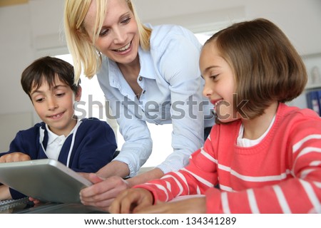 Teacher in class with kids using electronic tablet