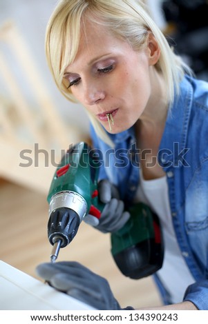 Woman at home using electric drill