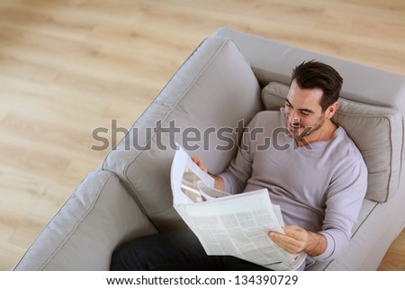 Upper view of man reading newspaper in sofa
