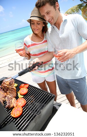 Cheerful couple in holidays preparing grilled meat