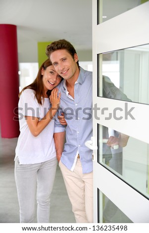 Cheerful couple inviting people to enter in home Cheerful couple inviting people to enter in home