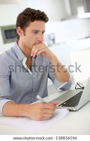 Closeup of smart guy working on laptop at home