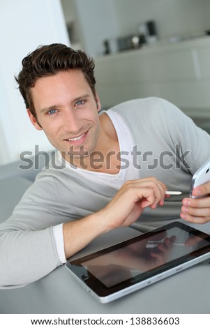Man in sofa using tablet and smartphone