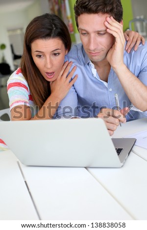 Couple looking at bank account with shocked expression