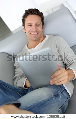 Adult man laying on sofa with tablet